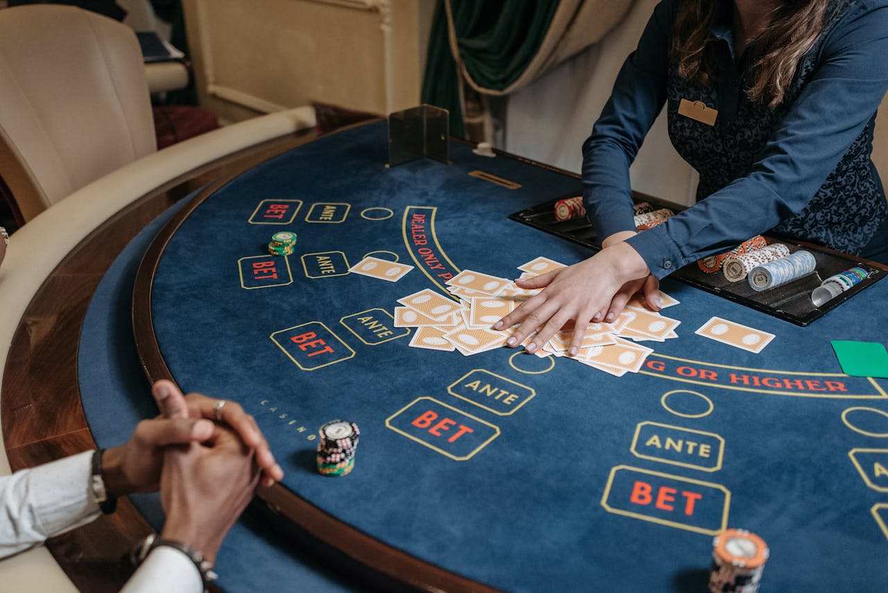 iWin88 official malaysia Close-up of a casino dealer shuffling cards on a gambling table with chips and bet labels.